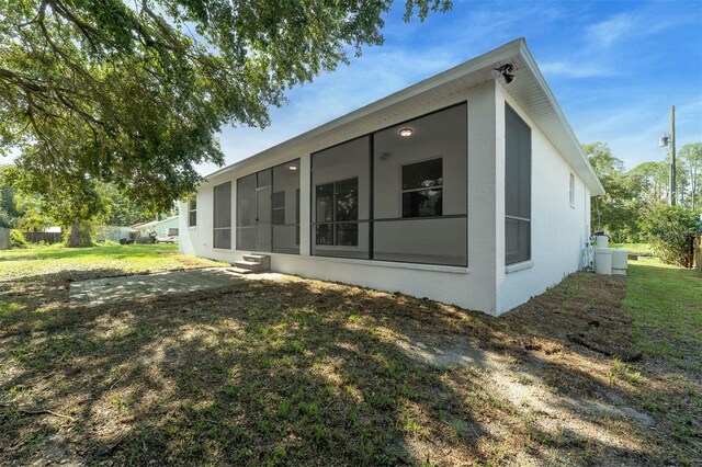 6479 Apple St, Saint Cloud, FL 34771 - rear view of house with a sunroom, a lawn, and stucco siding