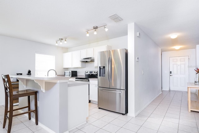 56 Levee Ln, Ormond Beach, FL 32174 - kitchen with stainless steel appliances, light tile patterned floors, under cabinet range hood, a kitchen breakfast bar, and white cabinetry