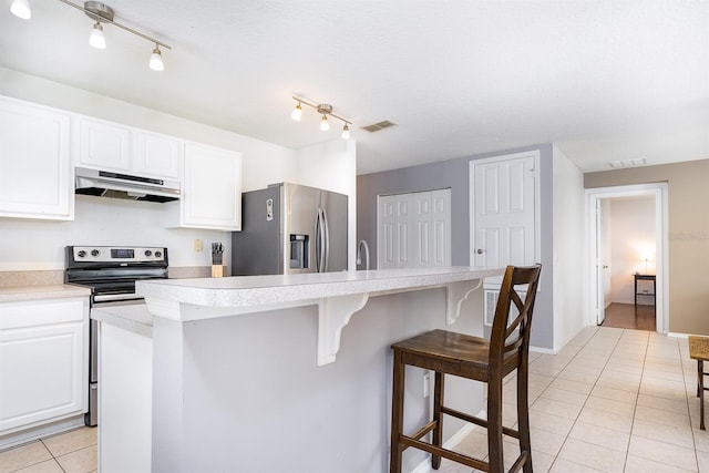 56 Levee Ln, Ormond Beach, FL 32174 - kitchen with appliances with stainless steel finishes, under cabinet range hood, light tile patterned flooring, a breakfast bar, and light countertops