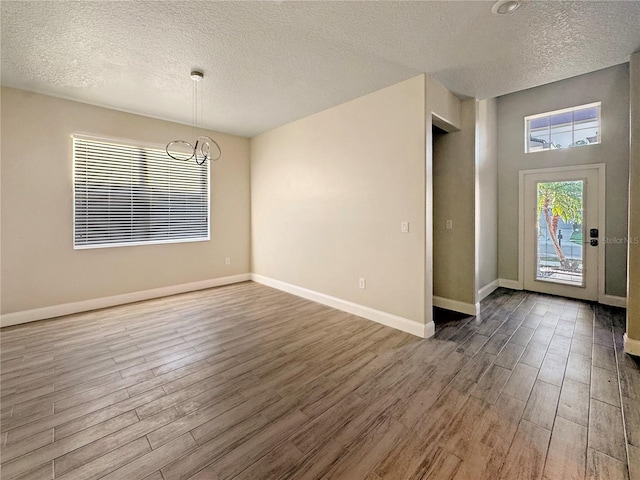 2164 Crosston Cir, Orlando, FL 32824 - entryway featuring wood finished floors, a textured ceiling, a chandelier, and baseboards