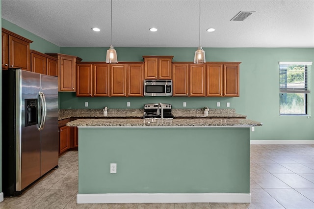 1394 Palmetto Dunes St, Champions Gate, FL 33896 - kitchen featuring appliances with stainless steel finishes, a textured ceiling, a center island with sink, brown cabinetry, and light stone countertops