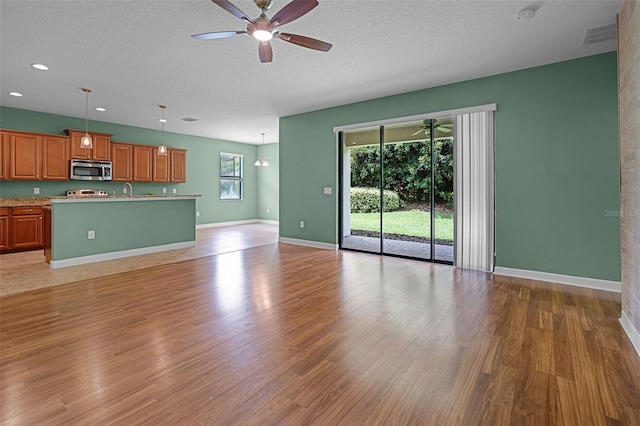 1394 Palmetto Dunes St, Champions Gate, FL 33896 - unfurnished living room featuring a ceiling fan, light wood-style floors, baseboards, a textured ceiling, and recessed lighting