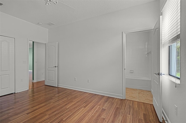 1394 Palmetto Dunes St, Champions Gate, FL 33896 - unfurnished bedroom with wood finished floors, a textured ceiling, connected bathroom, and baseboards