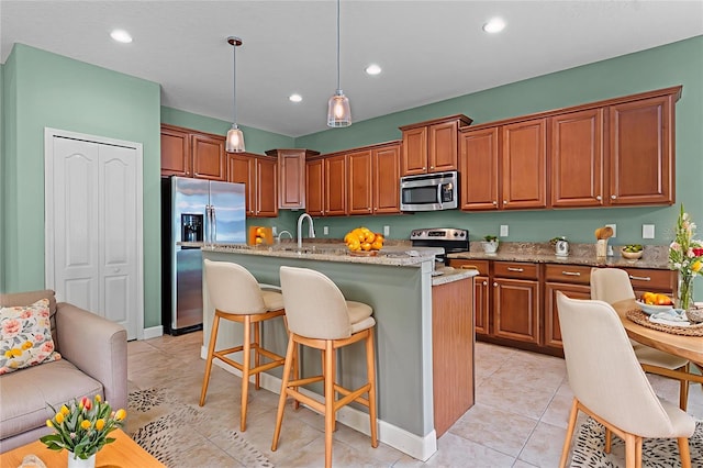 1394 Palmetto Dunes St, Champions Gate, FL 33896 - kitchen featuring stainless steel appliances, a kitchen island with sink, a kitchen breakfast bar, hanging light fixtures, and light stone counters
