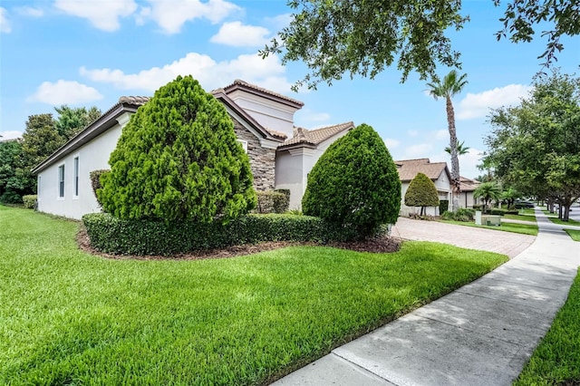 1394 Palmetto Dunes St, Champions Gate, FL 33896 - view of property exterior with stucco siding, a tiled roof, stone siding, and a yard