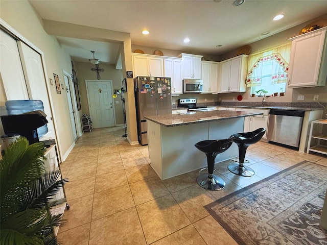 3333 Sagebrush St, Harmony, FL 34773 - kitchen featuring stainless steel appliances, a kitchen island, white cabinets, light tile patterned flooring, and recessed lighting
