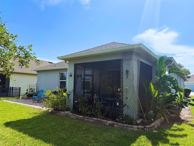3333 Sagebrush St, Harmony, FL 34773 - rear view of property with a sunroom, stucco siding, a lawn, a patio area, and roof with shingles