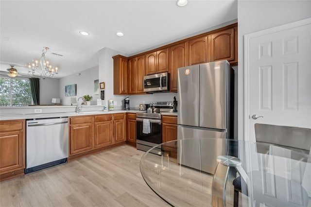5038 Tideview Cir Unit 21, Orlando, FL 32819 - kitchen featuring appliances with stainless steel finishes, a chandelier, light wood-style flooring, brown cabinets, and recessed lighting