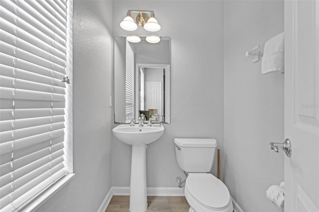 5038 Tideview Cir Unit 21, Orlando, FL 32819 - half bath featuring toilet, a sink, baseboards, and wood finished floors