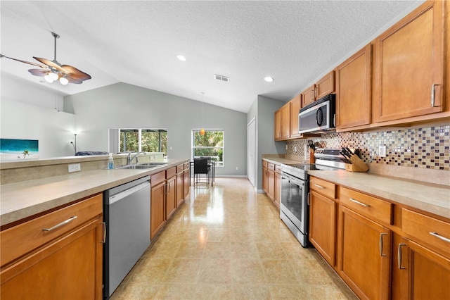4726 Ashurst St, Kissimmee, FL 34758 - kitchen featuring appliances with stainless steel finishes, vaulted ceiling, brown cabinetry, tasteful backsplash, and light countertops