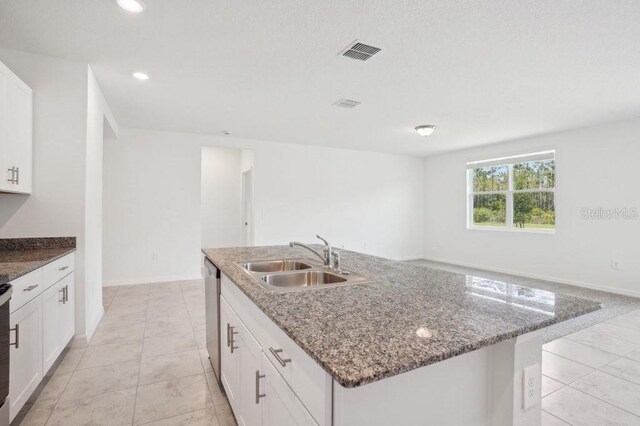 3214 Viceroy Ct, Kissimmee, FL 34759 - kitchen featuring stainless steel dishwasher, a sink, white cabinetry, stone counters, and a center island with sink