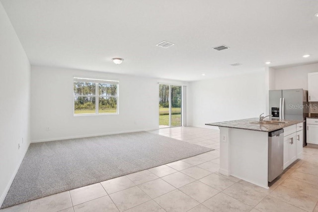 3214 Viceroy Ct, Kissimmee, FL 34759 - kitchen with stainless steel appliances, open floor plan, a sink, white cabinetry, and light stone counters
