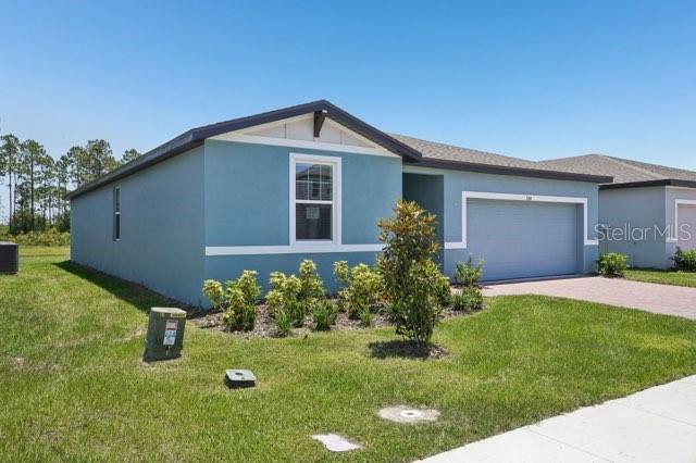 3214 Viceroy Ct, Kissimmee, FL 34759 - view of front of property with an attached garage, driveway, a front lawn, stucco siding, and cooling unit