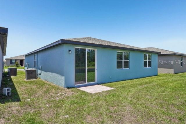 3214 Viceroy Ct, Kissimmee, FL 34759 - back of house featuring central AC unit, stucco siding, and a yard