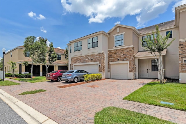 1628 Portofino Meadows Blvd, Orlando, FL 32824 - townhome / multi-family property featuring stone siding, stucco siding, an attached garage, and driveway