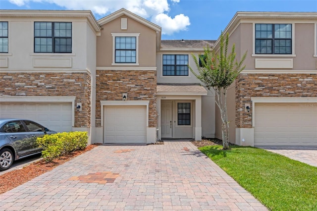 1628 Portofino Meadows Blvd, Orlando, FL 32824 - townhome / multi-family property featuring stone siding, decorative driveway, a garage, and stucco siding