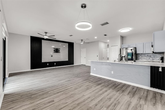 1628 Portofino Meadows Blvd, Orlando, FL 32824 - unfurnished living room with a ceiling fan, light wood finished floors, baseboards, and a sink
