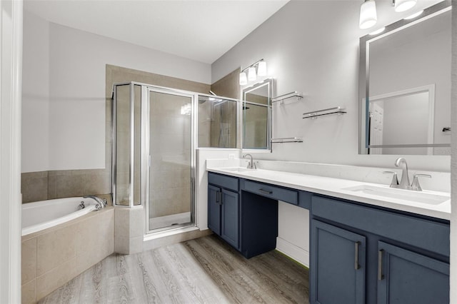 1628 Portofino Meadows Blvd, Orlando, FL 32824 - bathroom featuring double vanity, a shower stall, a garden tub, and wood finished floors