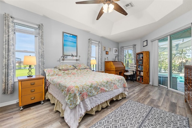 1760 Boat Launch Rd, Kissimmee, FL 34746 - bedroom featuring access to exterior, light wood-type flooring, multiple windows, and a raised ceiling