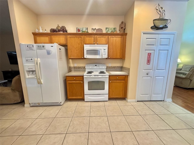 315 Wildflower Rd, Davenport, FL 33837 - kitchen featuring white appliances, brown cabinets, light countertops, light tile patterned floors, and baseboards