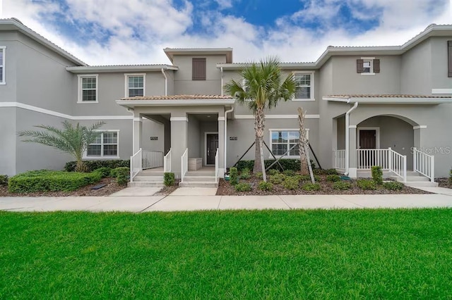 4903 Windermere Ave, Kissimmee, FL 34746 - view of front of home featuring a porch, a tiled roof, stucco siding, and a front yard