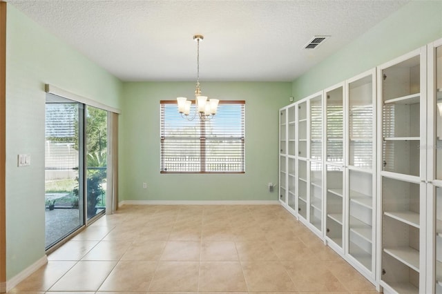 2416 White Poppy Dr, Kissimmee, FL 34747 - unfurnished room featuring a chandelier, tile patterned flooring, a textured ceiling, and baseboards