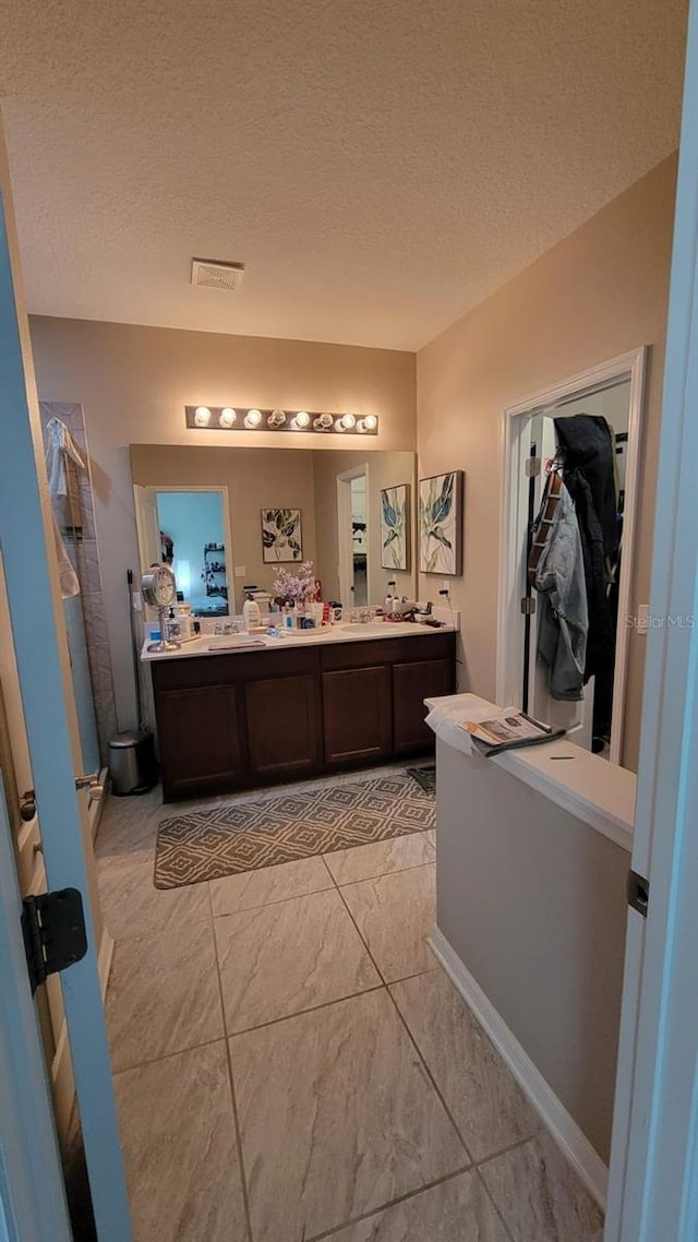 12372 Stone Bark Trl, Orlando, FL 32824 - full bathroom with a shower stall, a walk in closet, double vanity, a textured ceiling, and marble finish flooring