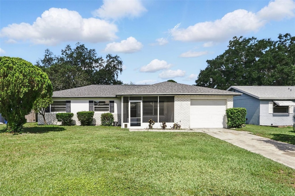412 Georgia Ave, Saint Cloud, FL 34769 - ranch-style home featuring a garage, driveway, a front lawn, brick siding, and a sunroom