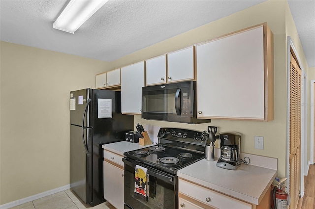 3151 Britannia Blvd Unit C, Kissimmee, FL 34747 - kitchen featuring black appliances, light countertops, white cabinetry, baseboards, and a textured ceiling