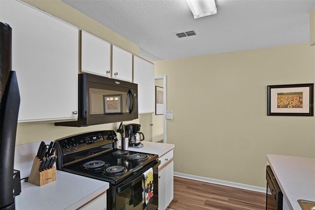 3151 Britannia Blvd Unit C, Kissimmee, FL 34747 - kitchen with black appliances, white cabinets, wood finished floors, light countertops, and baseboards