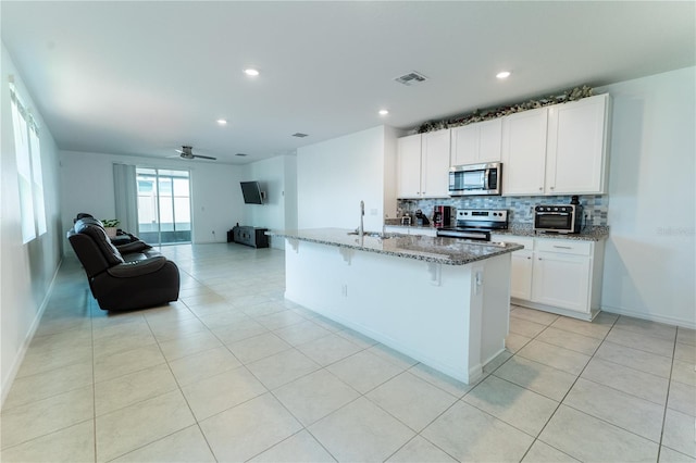 3442 Monaco Ln, Davenport, FL 33897 - kitchen featuring appliances with stainless steel finishes, light stone counters, backsplash, light tile patterned floors, and open floor plan