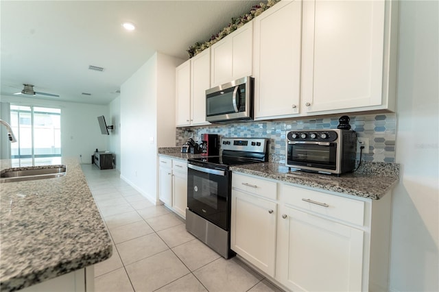 3442 Monaco Ln, Davenport, FL 33897 - kitchen featuring stainless steel appliances, backsplash, light tile patterned flooring, light stone countertops, and white cabinets