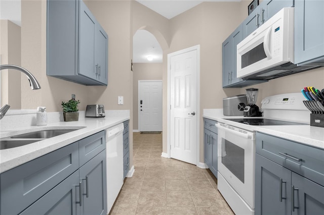 2307 Silver Palm Dr Unit 304, Kissimmee, FL 34747 - kitchen featuring white appliances, a sink, arched walkways, baseboards, and light tile patterned flooring