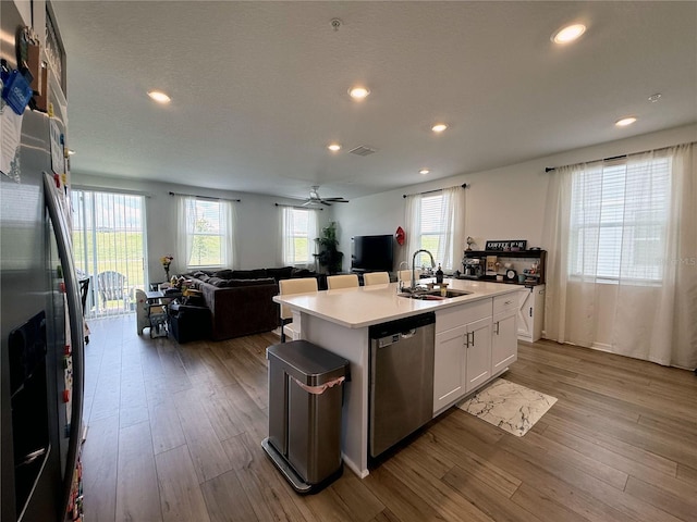 2086 Crape Jasmine Ln, Orlando, FL 32824 - kitchen featuring appliances with stainless steel finishes, a sink, open floor plan, wood finished floors, and white cabinetry
