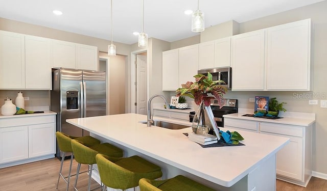 746 Lake Dell Ave, Dundee, FL 33838 - kitchen featuring stainless steel appliances, light wood-style flooring, white cabinets, a kitchen breakfast bar, and a sink