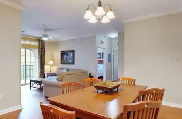 1375 Tuscana Ln Unit 1405, Davenport, FL 33896 - dining area featuring a chandelier, wood finished floors, baseboards, crown molding, and ceiling fan