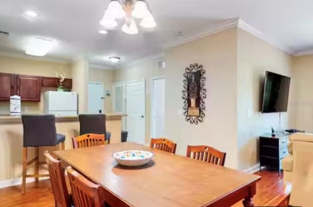 1375 Tuscana Ln Unit 1405, Davenport, FL 33896 - dining room featuring a chandelier, crown molding, light wood-style flooring, and baseboards