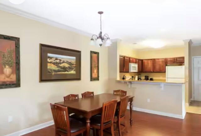1375 Tuscana Ln Unit 1405, Davenport, FL 33896 - dining room featuring dark wood-style flooring, a chandelier, ornamental molding, and baseboards