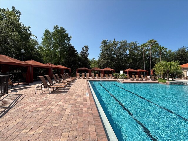 1375 Tuscana Ln Unit 1405, Davenport, FL 33896 - community pool with a gazebo, a patio, and view of scattered trees
