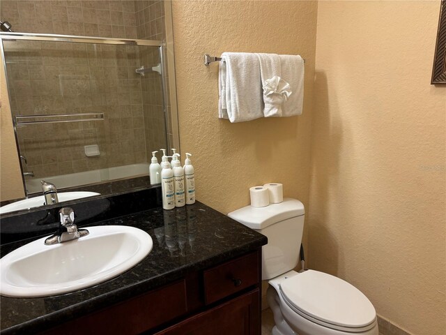 1375 Tuscana Ln Unit 1405, Davenport, FL 33896 - bathroom featuring a textured wall, toilet, vanity, and bath / shower combo with glass door