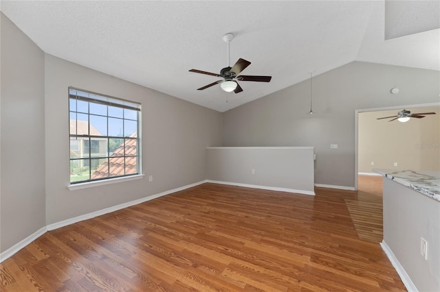 437 Fountainhead Cir Unit 283, Kissimmee, FL 34741 - spare room featuring a ceiling fan, lofted ceiling, light wood finished floors, baseboards, and a textured ceiling