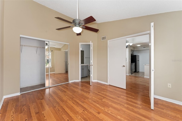 437 Fountainhead Cir Unit 283, Kissimmee, FL 34741 - unfurnished bedroom featuring light wood-style flooring, freestanding refrigerator, a closet, baseboards, and lofted ceiling