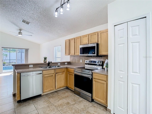 1851 Hammock Moss Dr, Orlando, FL 32820 - kitchen featuring appliances with stainless steel finishes, a sink, a peninsula, light brown cabinets, and lofted ceiling