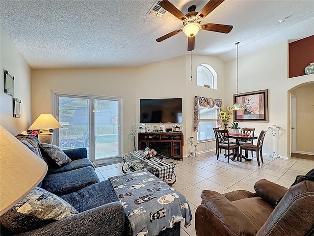 1364 Rebecca Dr, Haines City, FL 33844 - living room featuring ceiling fan, light tile patterned floors, arched walkways, a textured ceiling, and high vaulted ceiling