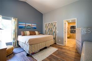 3030 Eagle Crossing Dr, Kissimmee, FL 34746 - bedroom with wood finished floors, high vaulted ceiling, and baseboards