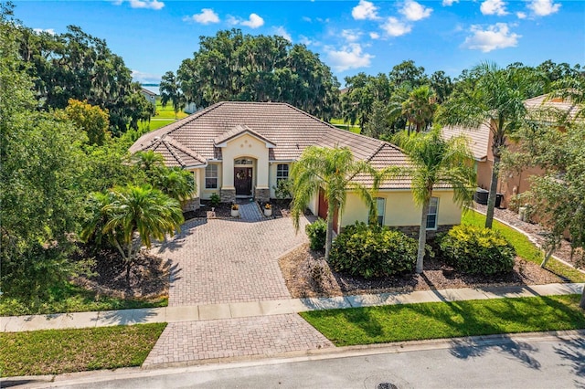 3427 Harborside Ct, Kissimmee, FL 34746 - mediterranean / spanish home with decorative driveway, a tiled roof, stucco siding, and stone siding