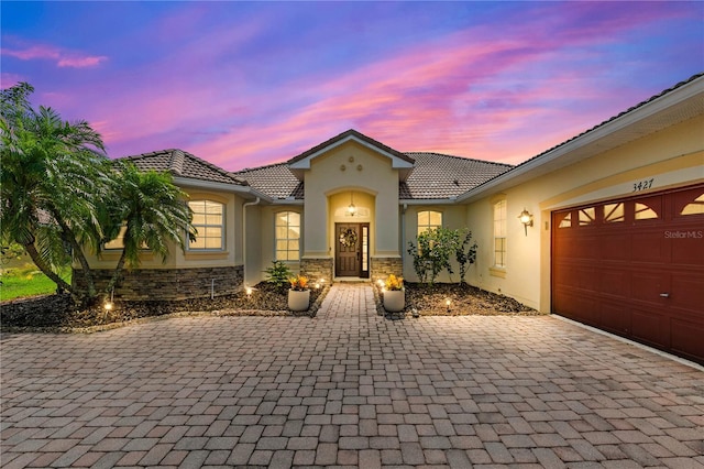 3427 Harborside Ct, Kissimmee, FL 34746 - mediterranean / spanish home featuring stucco siding, decorative driveway, a tiled roof, and an attached garage