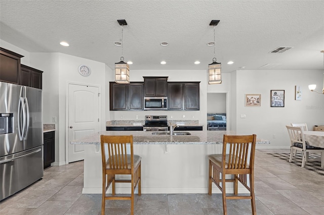 1951 Partin Terrace Rd, Kissimmee, FL 34744 - kitchen with appliances with stainless steel finishes, a kitchen bar, a kitchen island with sink, light stone countertops, and a sink