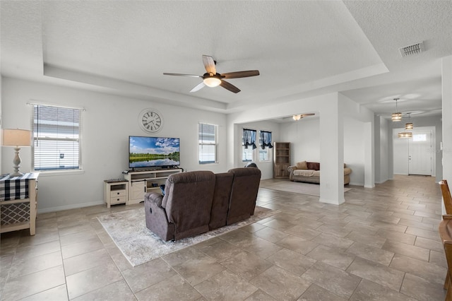 1951 Partin Terrace Rd, Kissimmee, FL 34744 - living room featuring a tray ceiling, ceiling fan, a textured ceiling, plenty of natural light, and baseboards