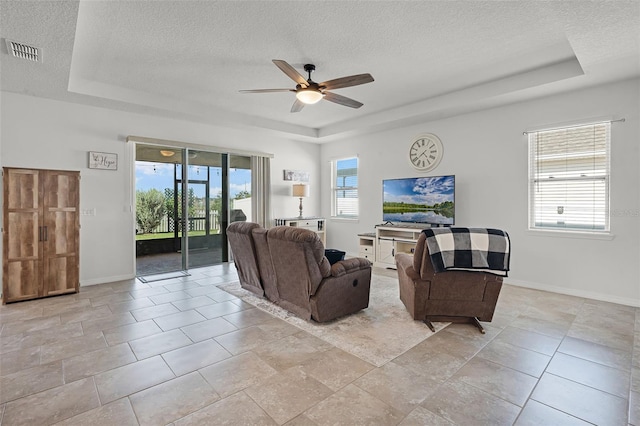1951 Partin Terrace Rd, Kissimmee, FL 34744 - living area featuring a tray ceiling, a textured ceiling, a ceiling fan, and healthy amount of natural light